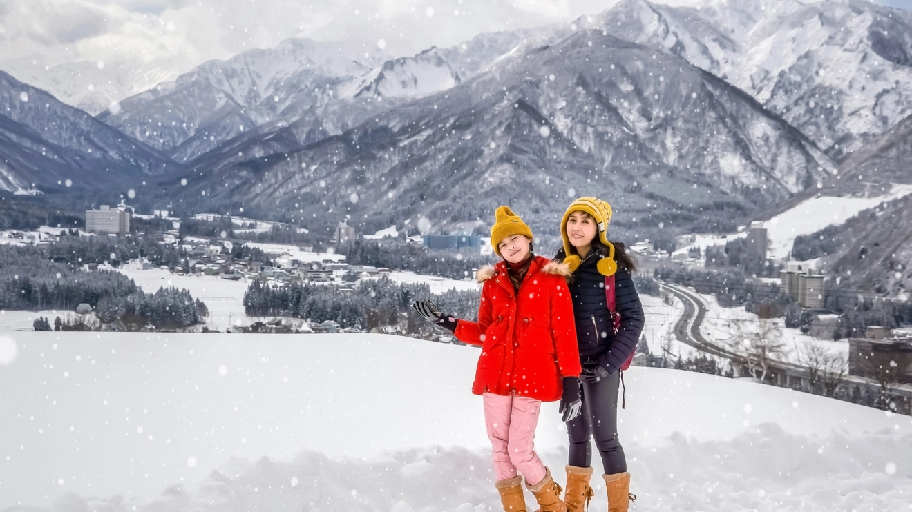 Mother and daughter pose for photo on a snowy hill in Japan. Image credit: stock.adobe.com