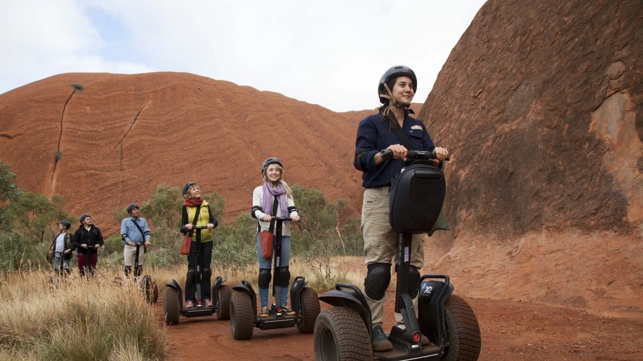 Small group of people on a Segway tour at the base of Uluru. Image: Tourism NT