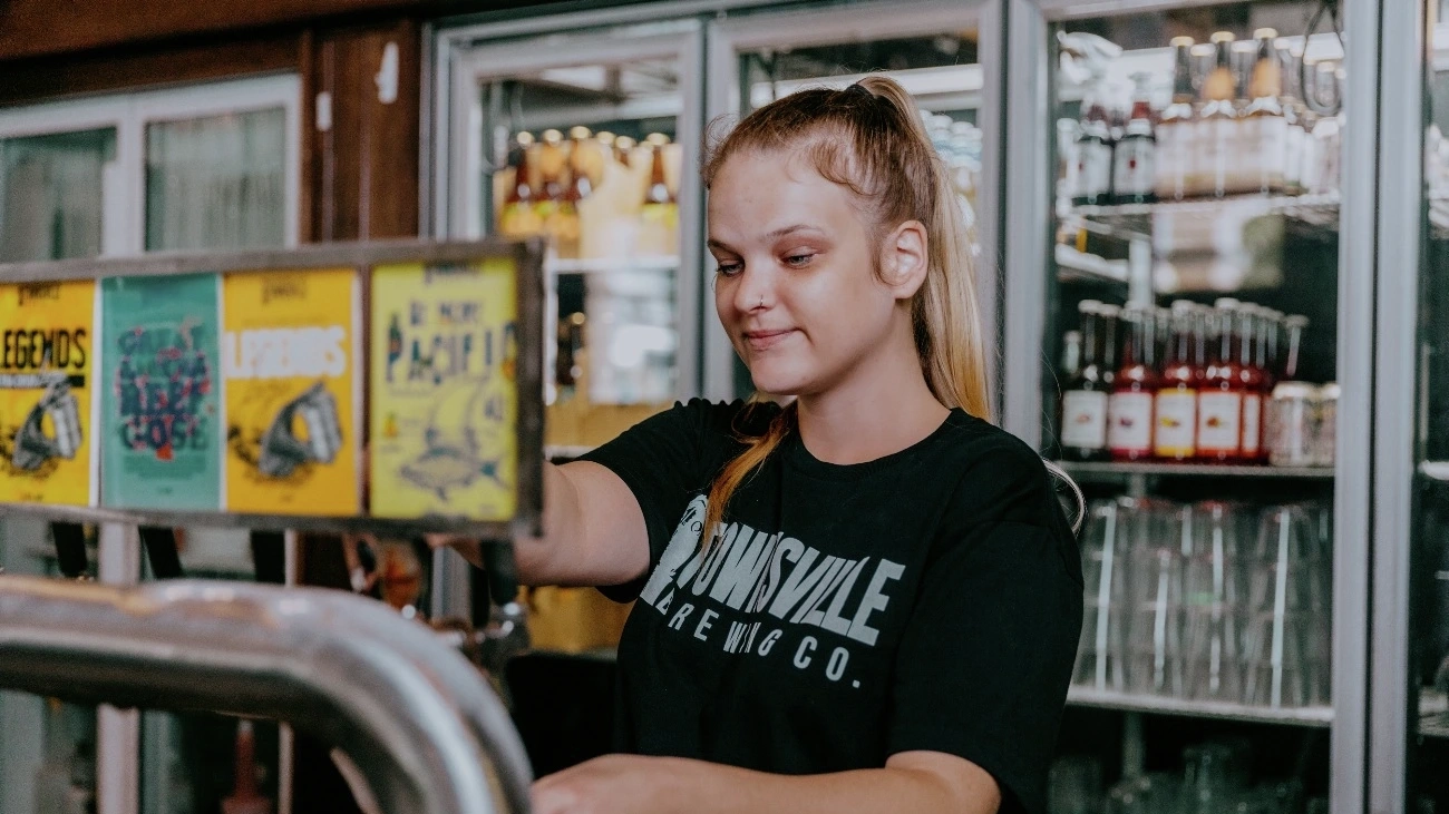 Young woman pulls a beer behind the bar at Townsville Brewery. Image credit: Townsville Brewing Company.