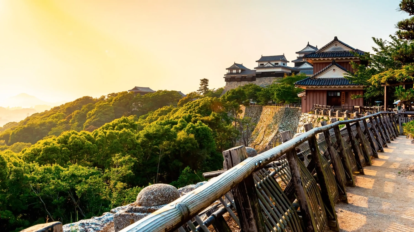 View of Matsuyama castle, fenced path and green forest, Matsuyama, Japan. Image credit: stock.adobe.com