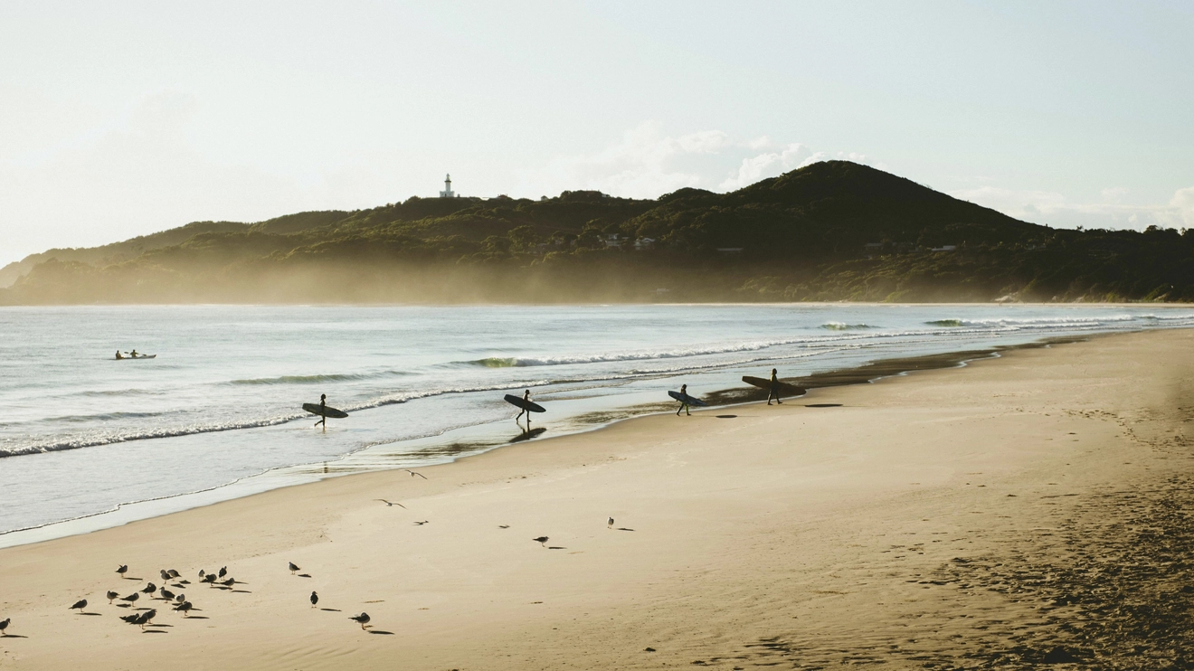 Surfers catching morning waves at Belongil Beach, Byron Bay. Image credit: Destination NSW