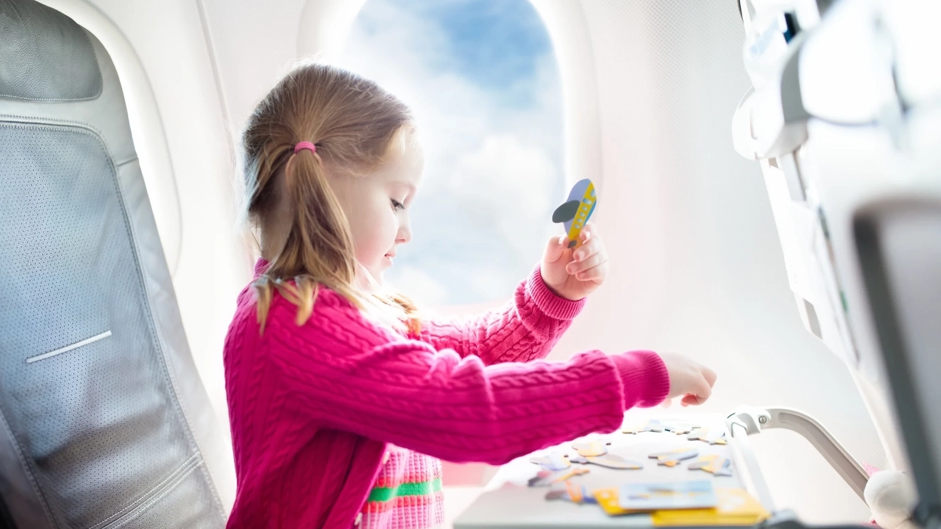 Little girl playing while on flight. Image credit: iStock