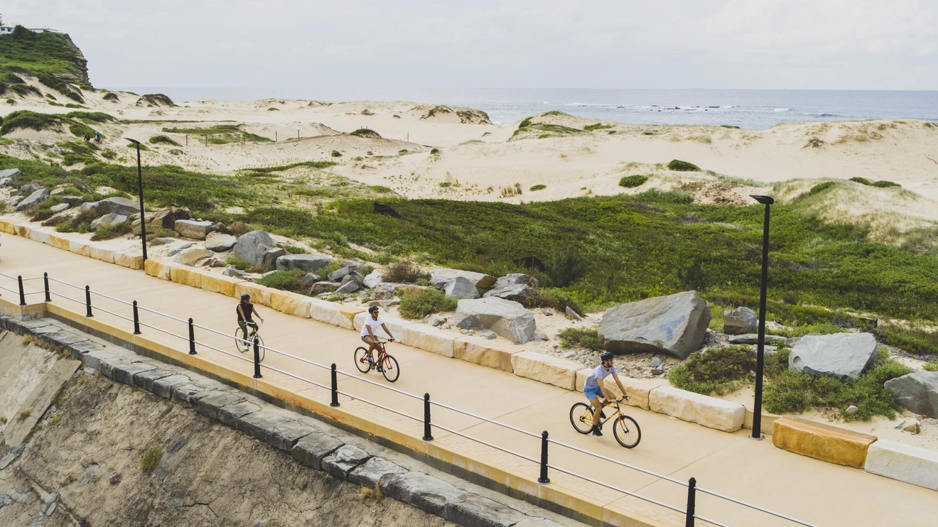 People riding bikes along Macquarie Pier at Nobbys Beach, Newcastle. Image credit: Destination NSW