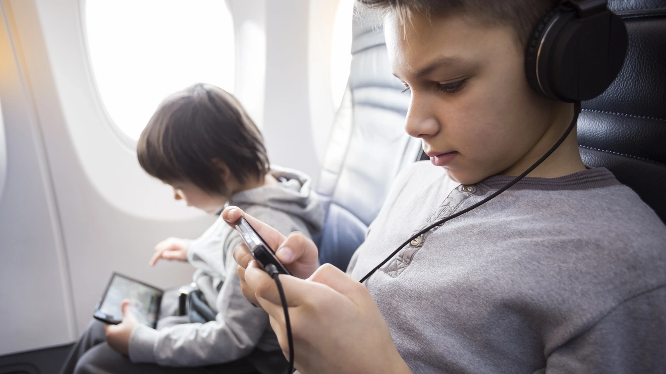 Kids are enjoying their gadgets while in flight. Image credit: iStock