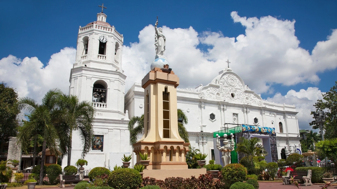 Façade of Cebu's historic Basilica del Santo Niño, with a statue and gardens in foreground. Image credit: stock.adobe.com