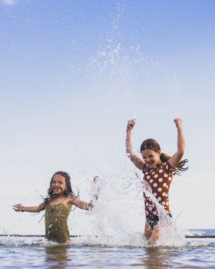Two children splashing in the water at Canoe Pool, Newcastle. Image credit: Destination NSW