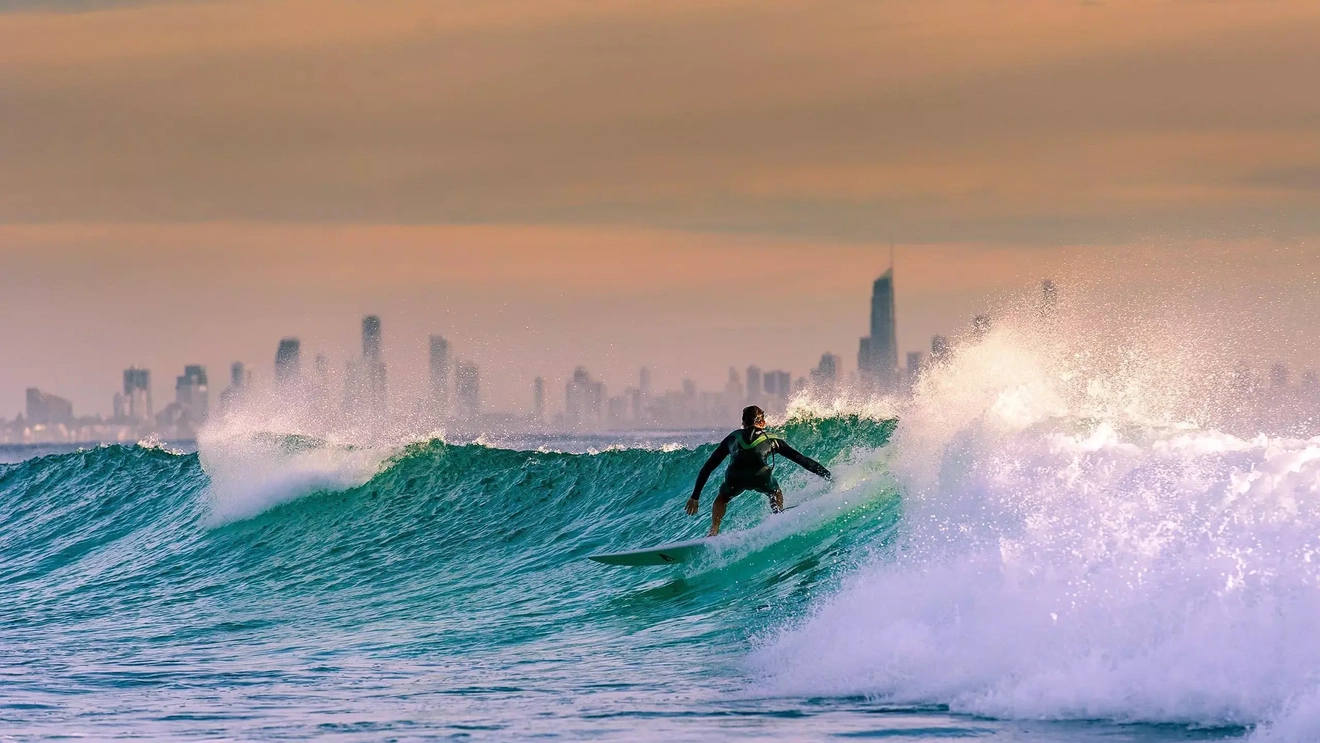 Một người đang lướt sóng với dãy khách sạn tại Surfers Paradise sừng sững trên đường chân trời nằm ở phía sau. Hình ảnh của: Shutterstock