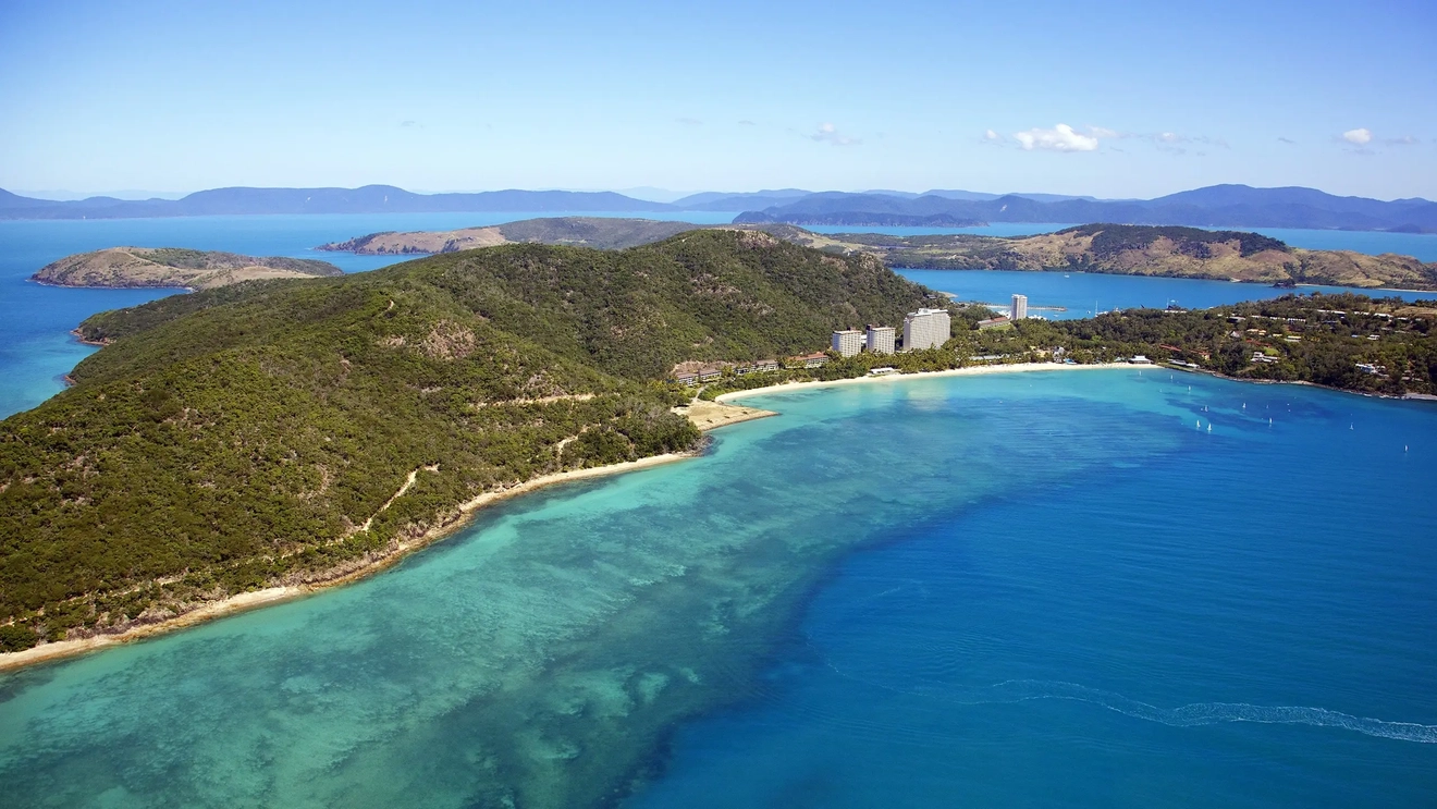 Foto udara Hamilton Island yang tertutup dedaunan dan dikelilingi oleh pantai dan resor, dikelilingi oleh perairan biru cerah. Kredit foto: Shutterstock