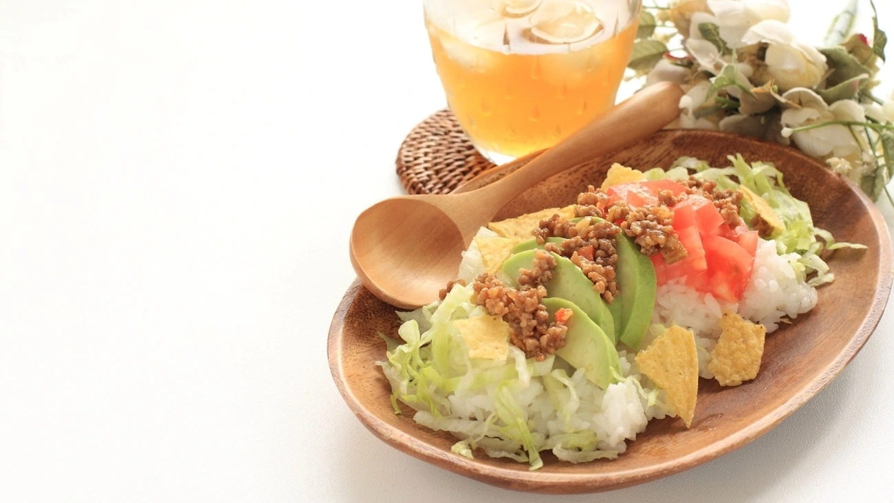 A plate of taco rice with avocados and tomatoes.