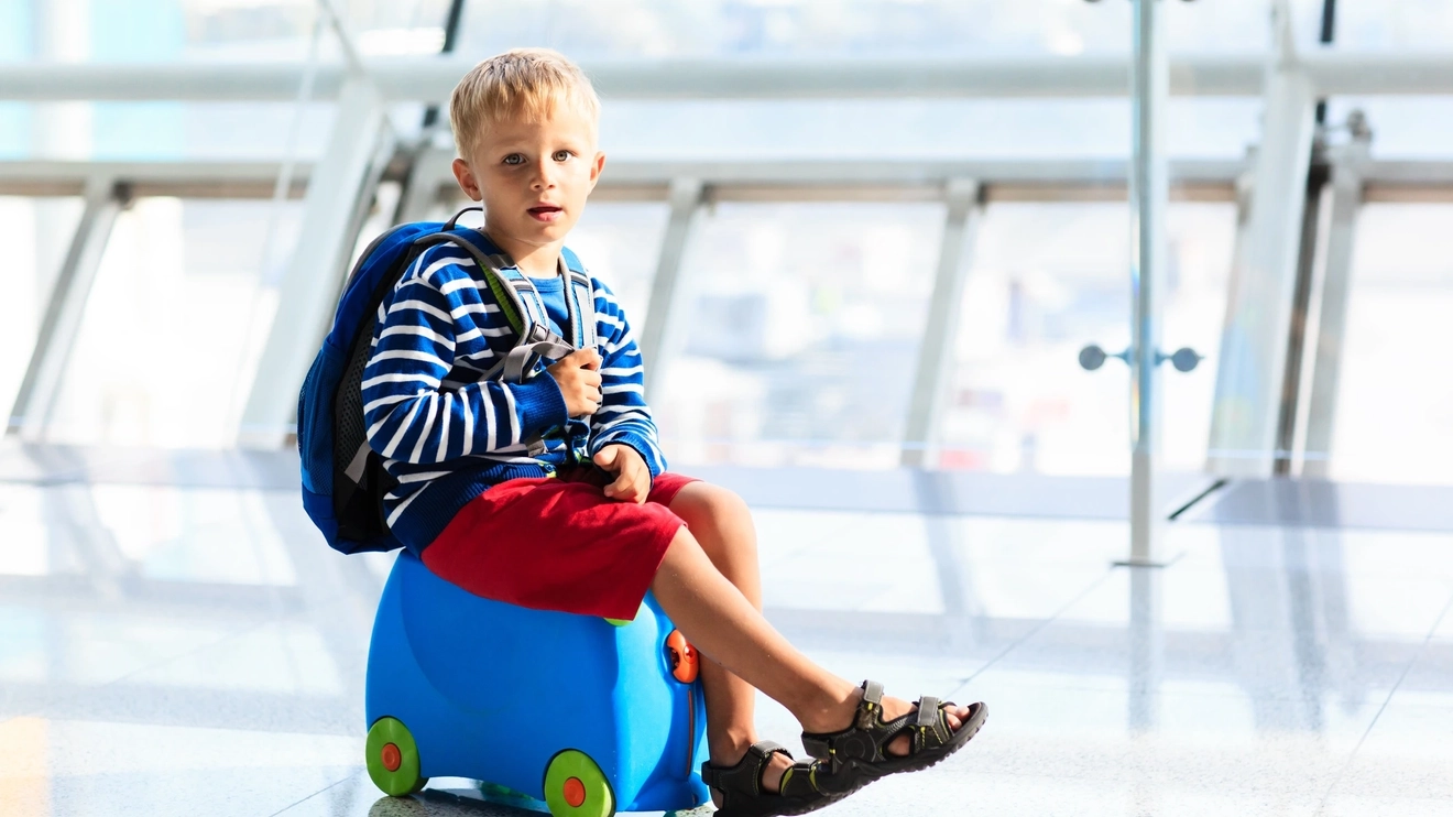 Little boy waiting in the airport with his own baggage. Image credit: iStock