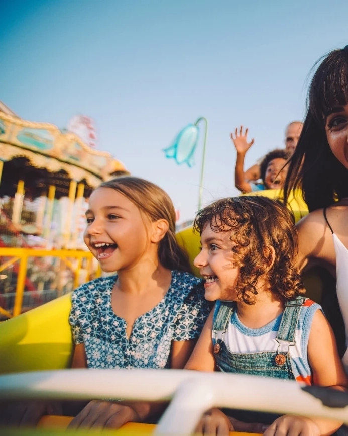 Kids enjoying theme park ride with their guardians.