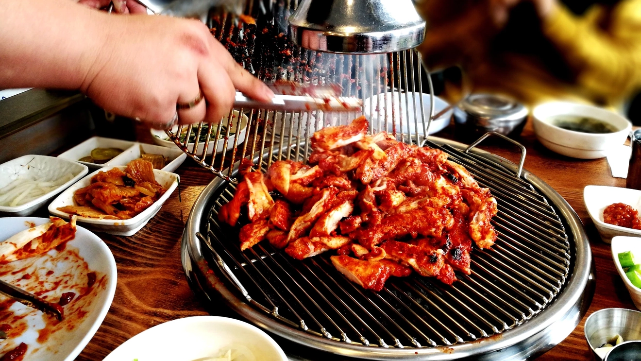 Person preparing Korean barbecue at the table in a restaurant in Seoul, South Korea. Image credit: stock.adobe.com