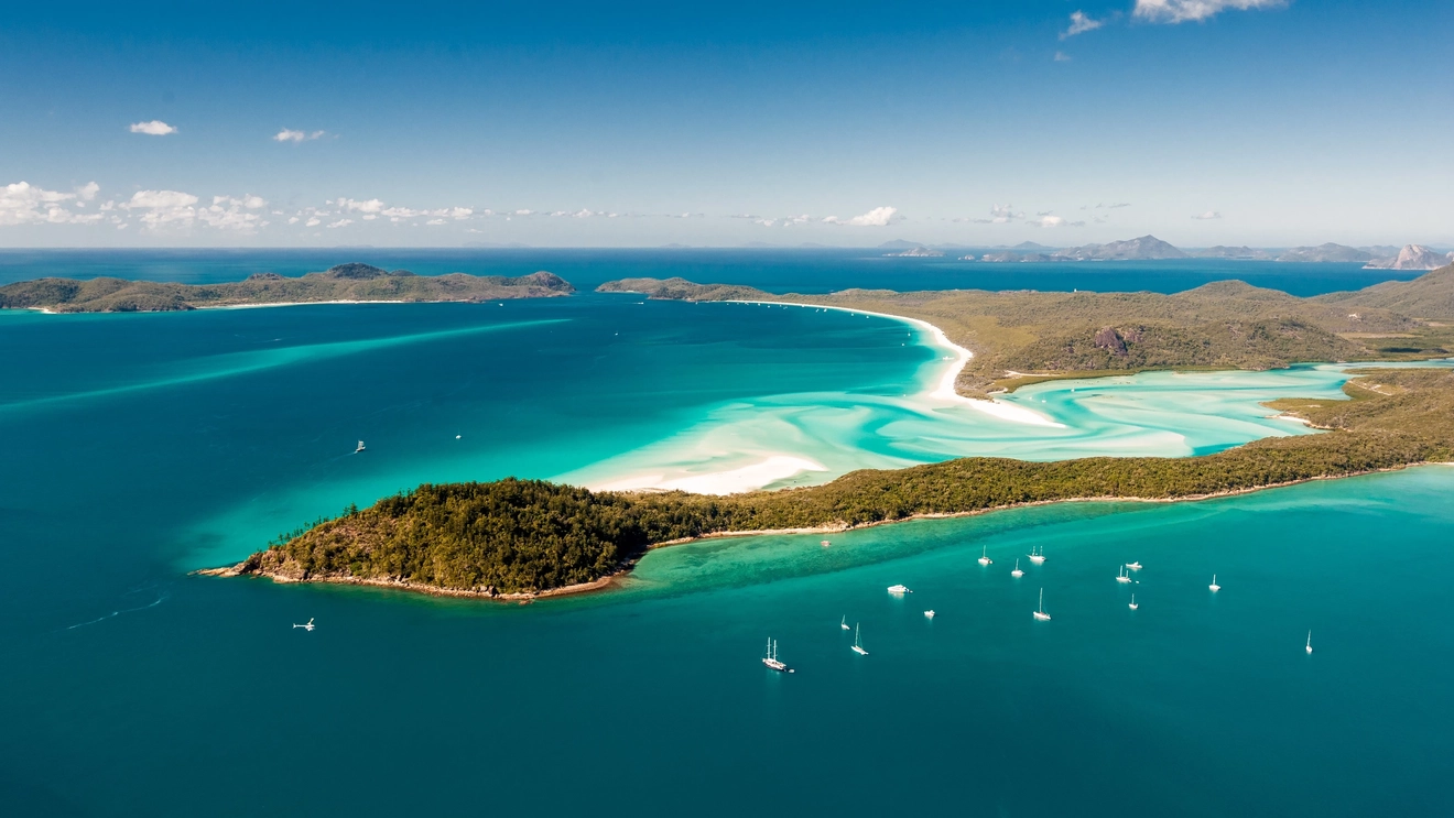 Aerial view of Hill Inlet’s swirling white sands and turquoise water, with sail boats moored off Whitsunday Island, Queensland. Image credit: stock.adobe.com