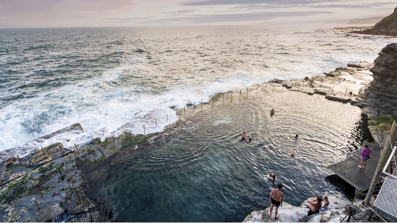 People swimming in the Bogey Hole in Newcastle at dusk. Image credit: Destination NSW