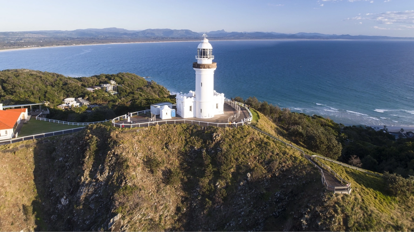 Aerial view of Cape Byron Lighthouse with ocean in the background on a sunny day, Byron Bay. Image credit: Destination NSW