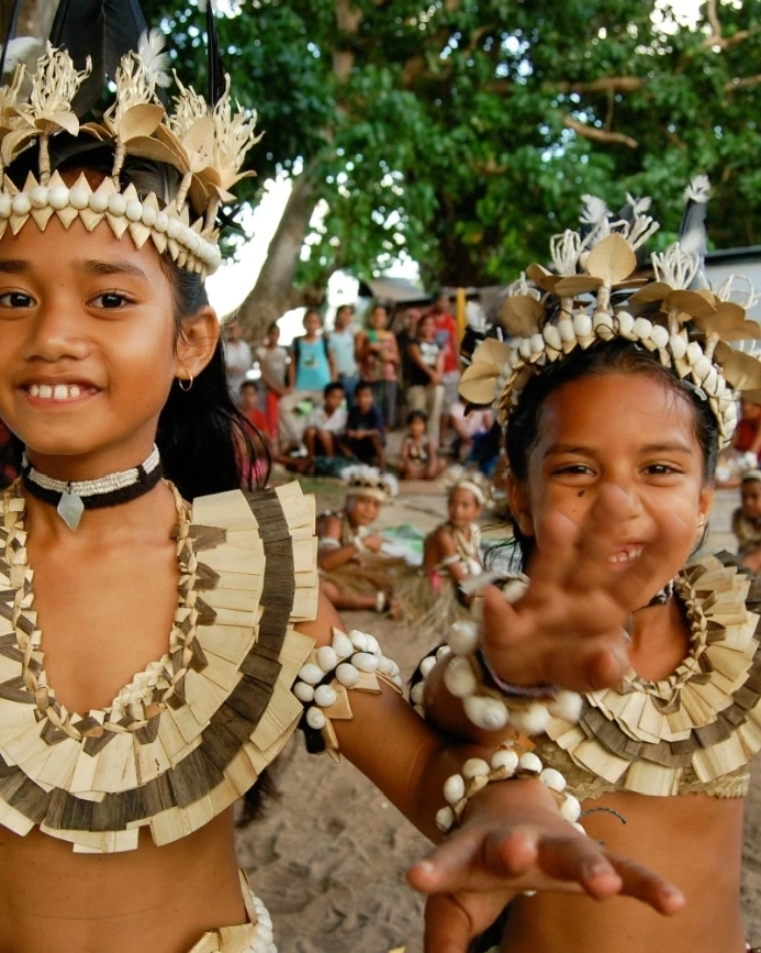 Two girls in traditional Fijian dress, with other children in the background. Image credit: stock.adobe.com