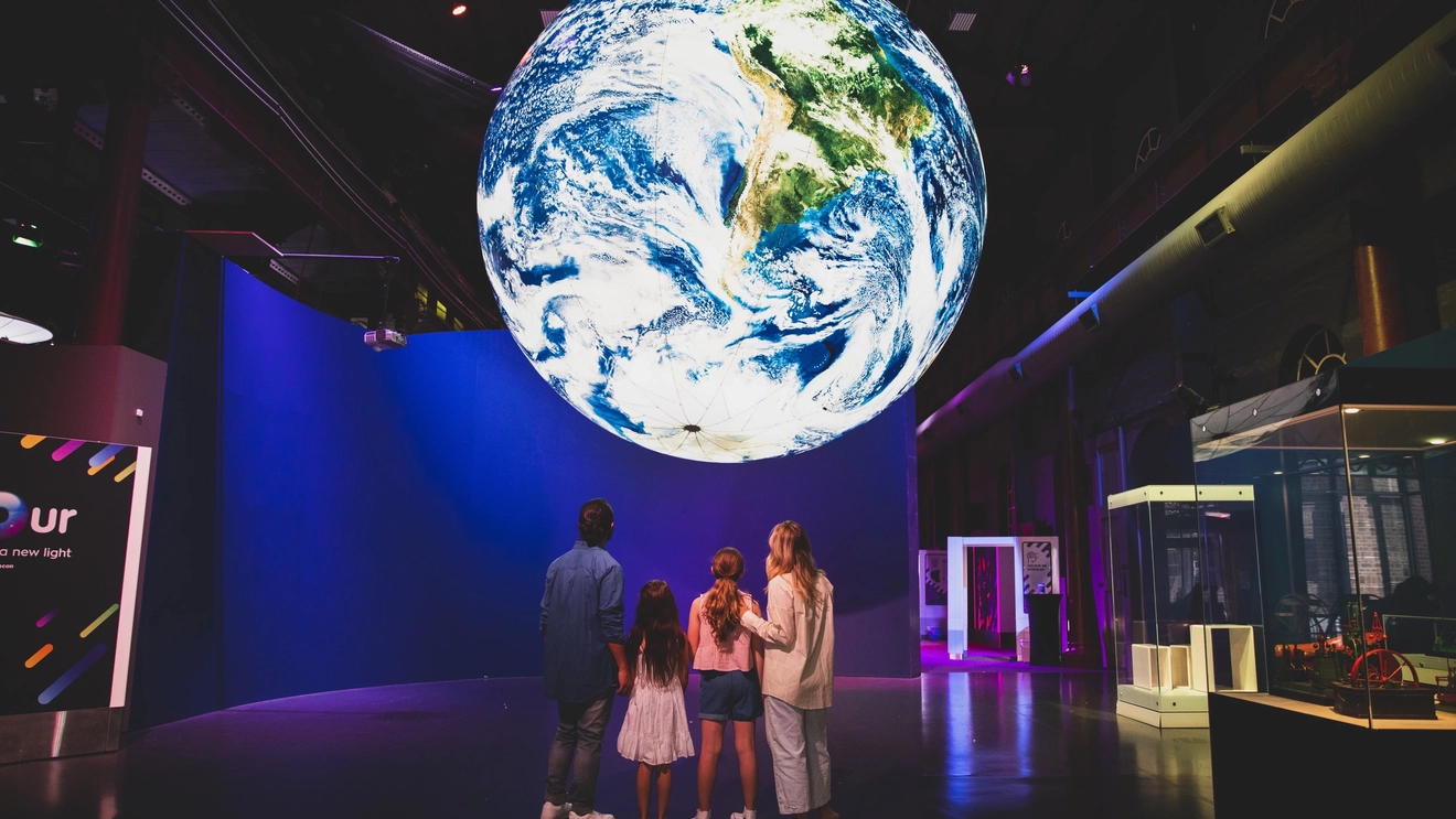 A family standing under a 5-metre globe at the Newcastle Museum. Image credit: Destination NSW