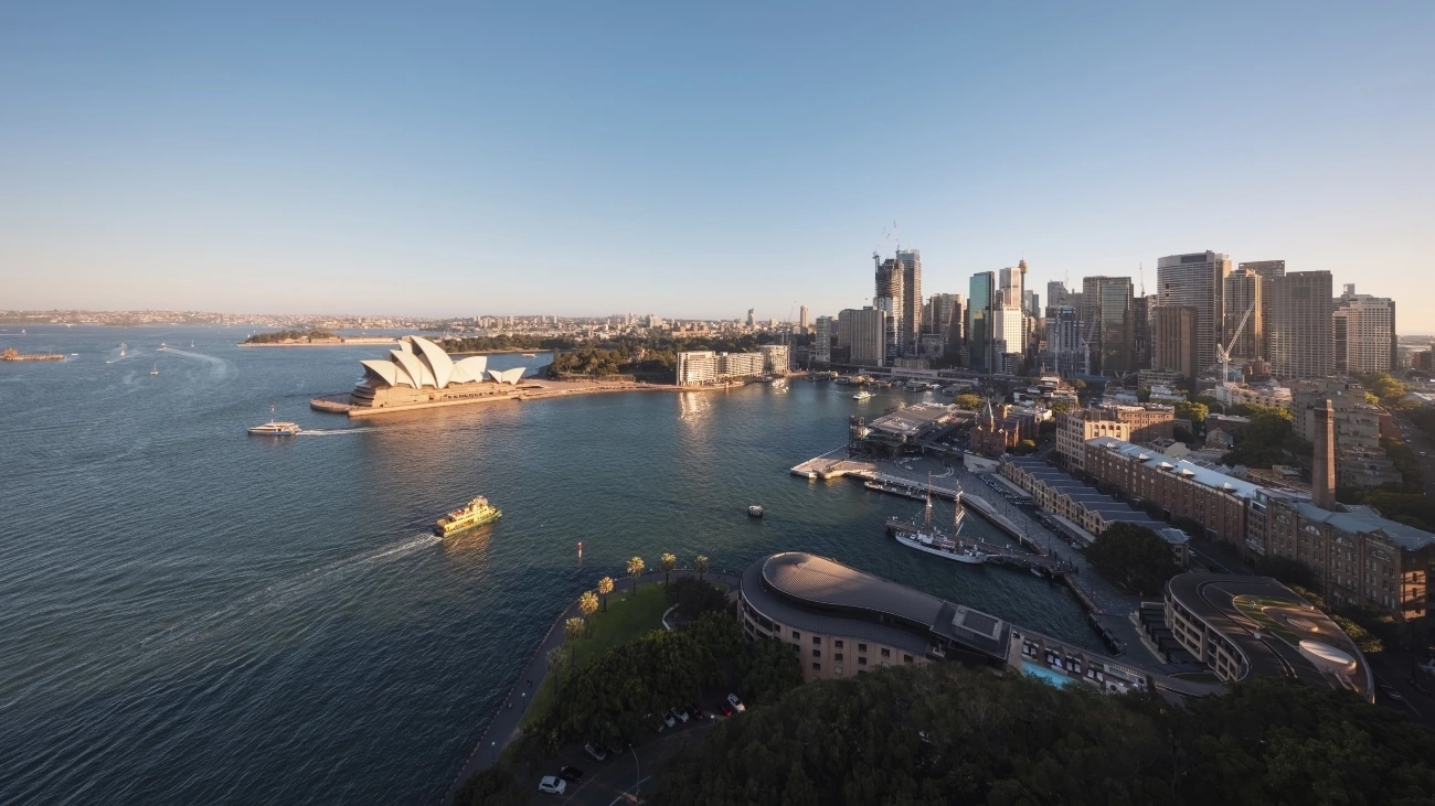 시드니 오페라 하우스를 지나 항해하는 페리들과 뒤로 펼쳐진 도시의 스카이라인이 어우러진 시드니 하버를 하늘에서 본 모습. 이미지 제공: Destination NSW