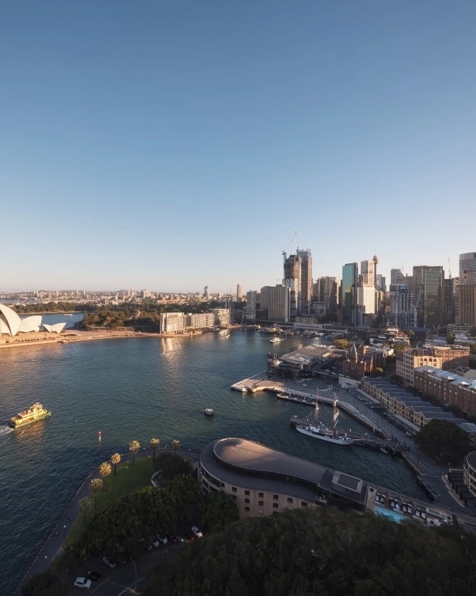 시드니 오페라 하우스를 지나 항해하는 페리들과 뒤로 펼쳐진 도시의 스카이라인이 어우러진 시드니 하버를 하늘에서 본 모습. 이미지 제공: Destination NSW