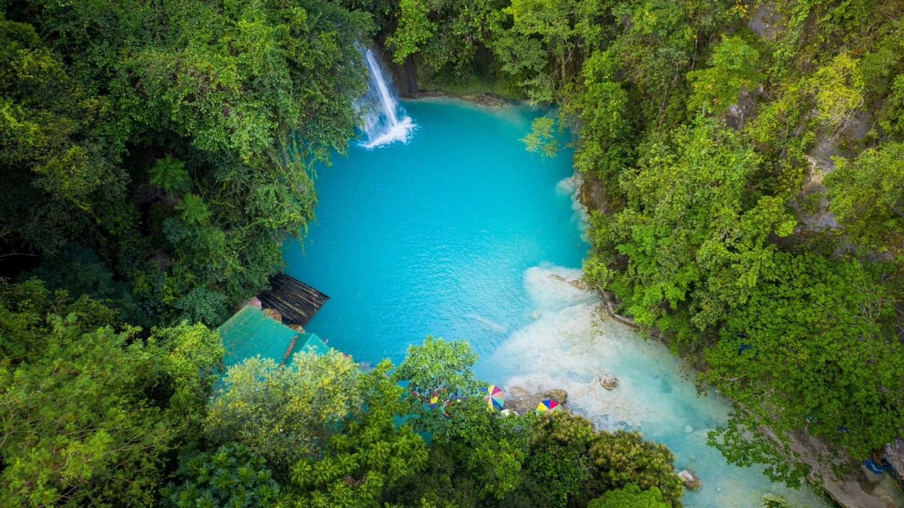 Aerial view of a turquoise swimming hole surrounded by jungle at the base of Kawasan Falls, Cebu. Image credit: stock.adobe.com