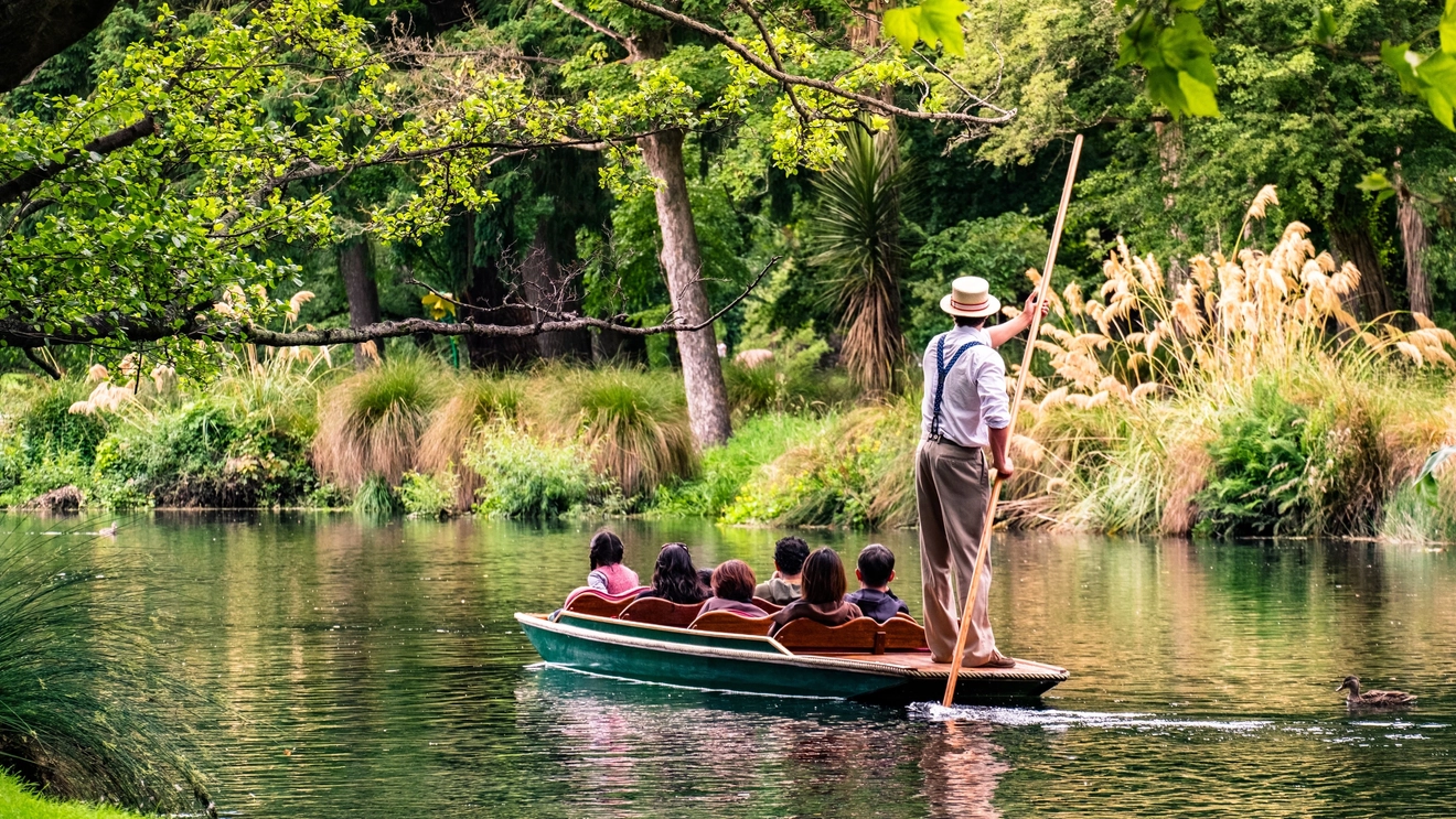 A punt with passengers floats down the Avon River through the Botanic Gardens, Christchurch, New Zealand. Image credit: stock.adobe.com