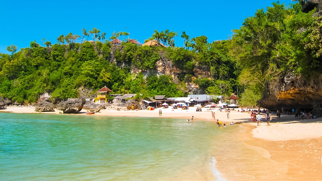 People in the water and on the sand at Padang Beach on a sunny day, Bali, Indonesia. Image credit: stock.adobe.com