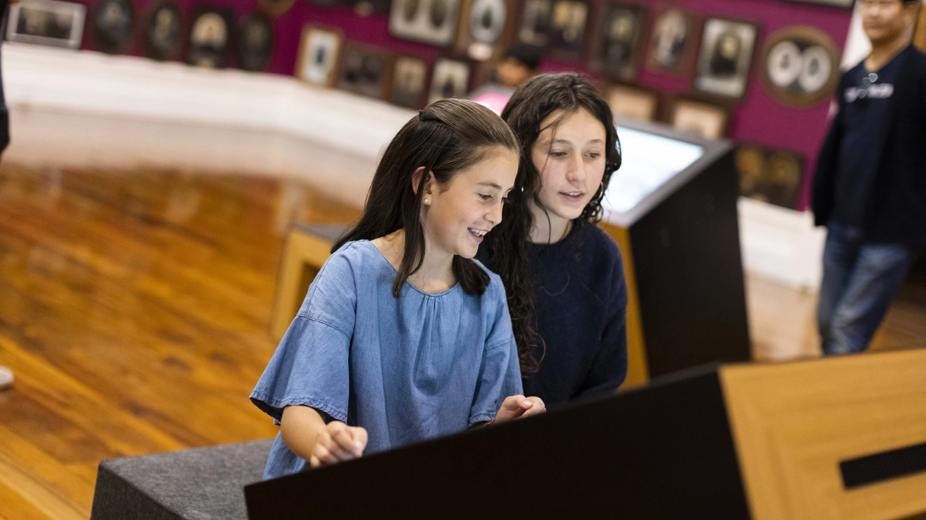 Two children use an interactive screen in a room of portraits at the Toitū Otago Settlers Museum, Dunedin, New Zealand. Image credit: Dunedin NZ