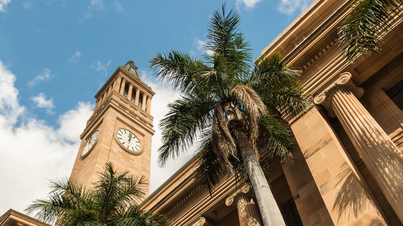 View of the sandstone columns and facade of Brisbane City Hall, looking up to the clock tower. Image credit: Shutterstock